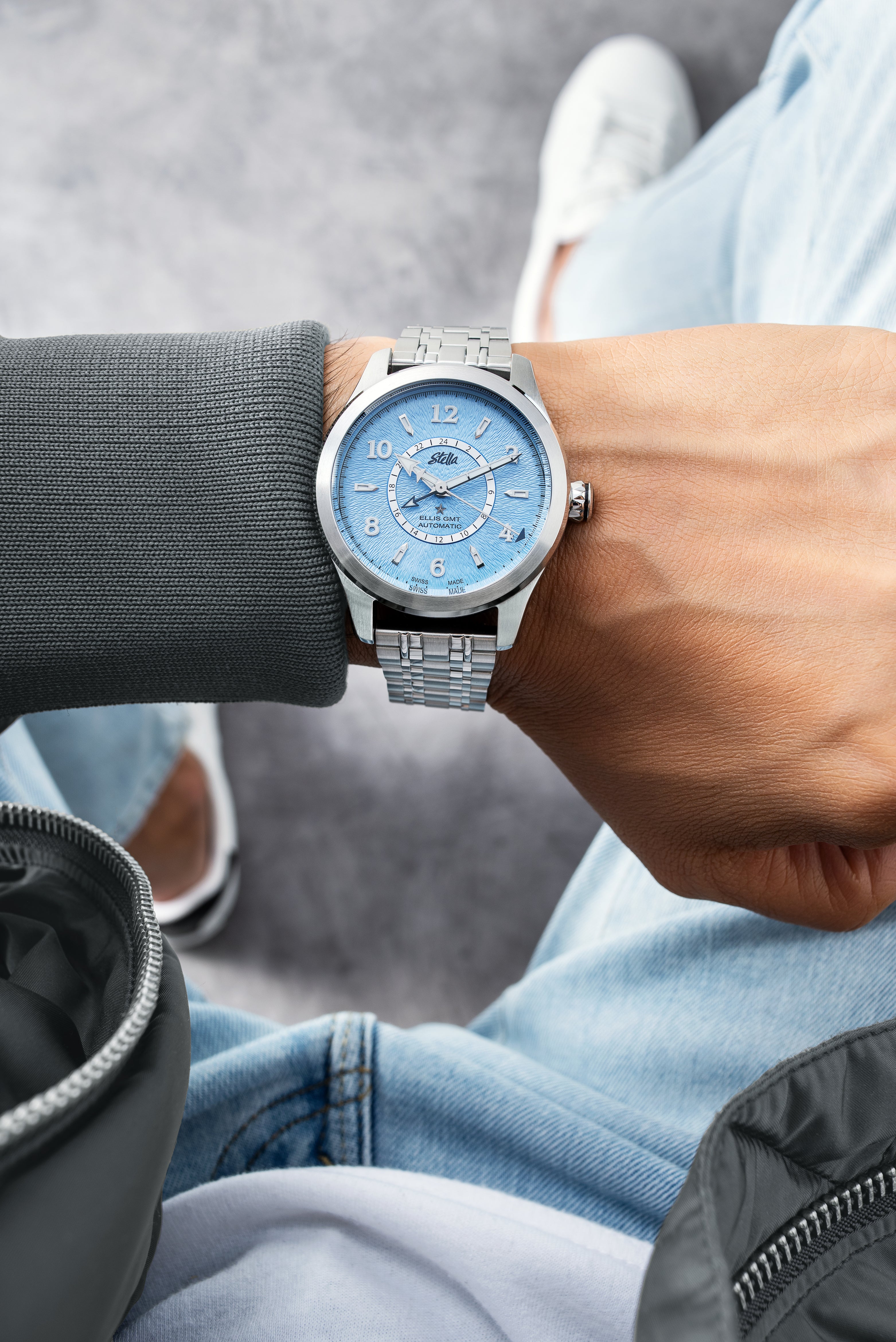 Person wearing a silver watch with a blue face on a blurred background
