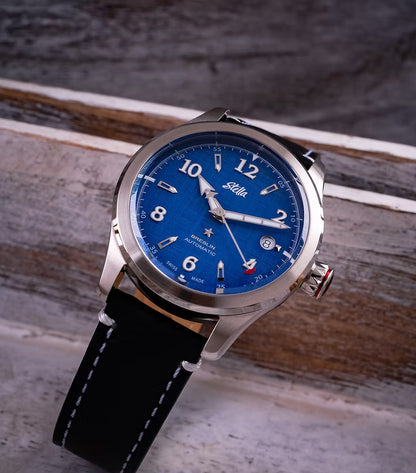 Stella watch with blue dial and black leather strap on a wooden surface