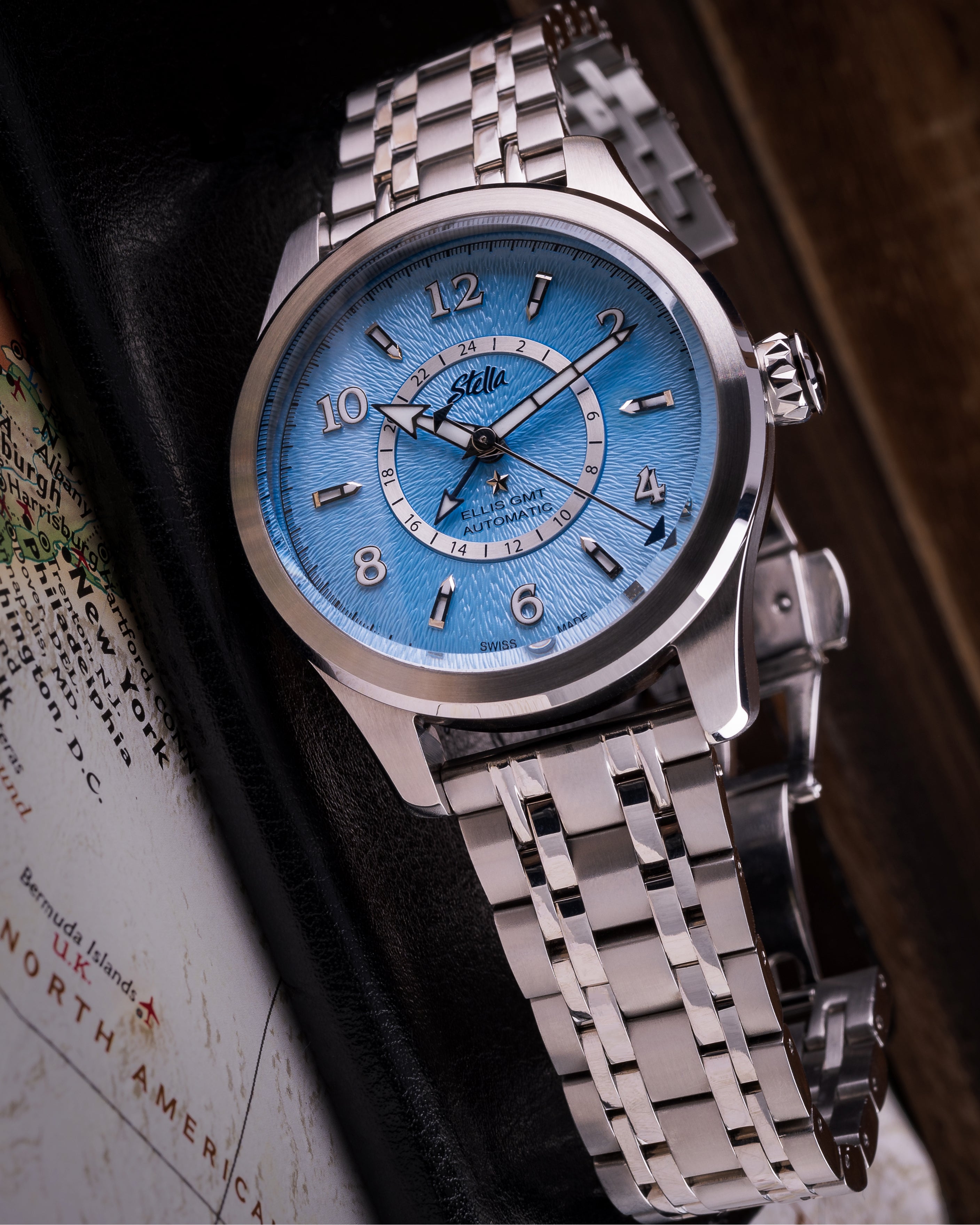 Silver watch with a blue face and silver bracelet on a map background