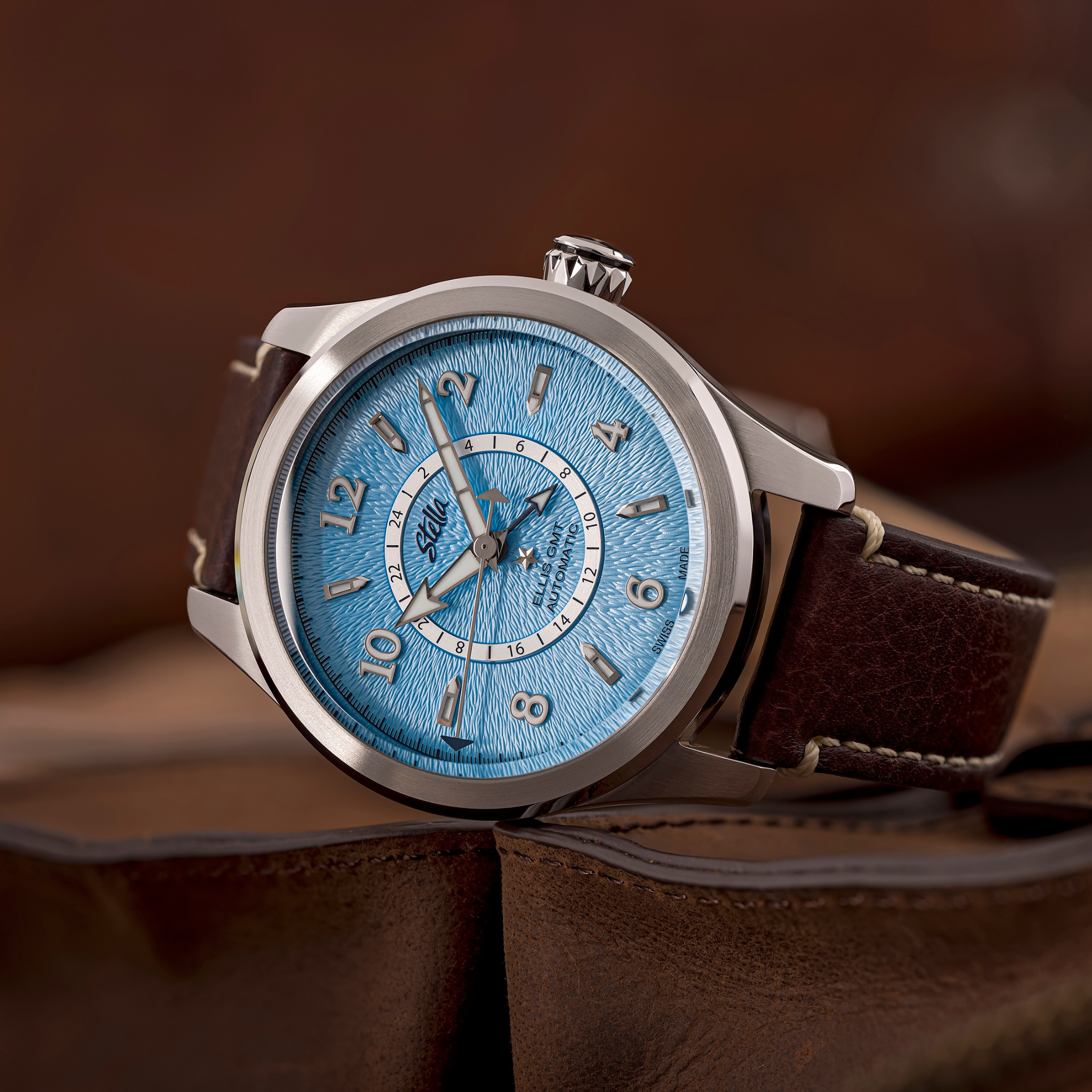 Watch with a blue face and brown leather strap on a brown background